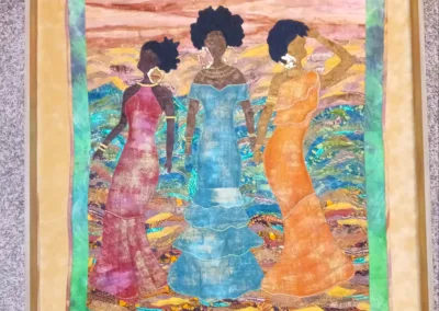A framed piece of art with three women in dresses.