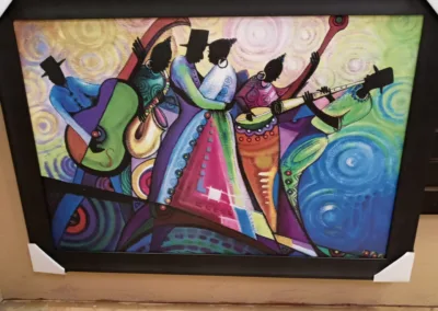 A framed painting of a group of people playing music.