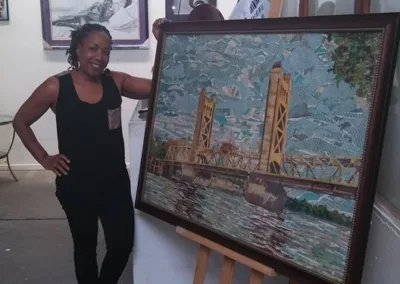 A woman standing next to a painting of a bridge.