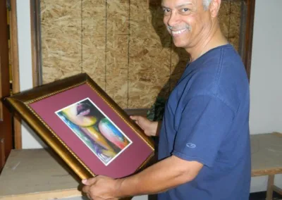 A man holding up a framed painting.
