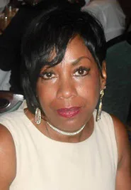 A woman in a beige dress is posing for a picture.